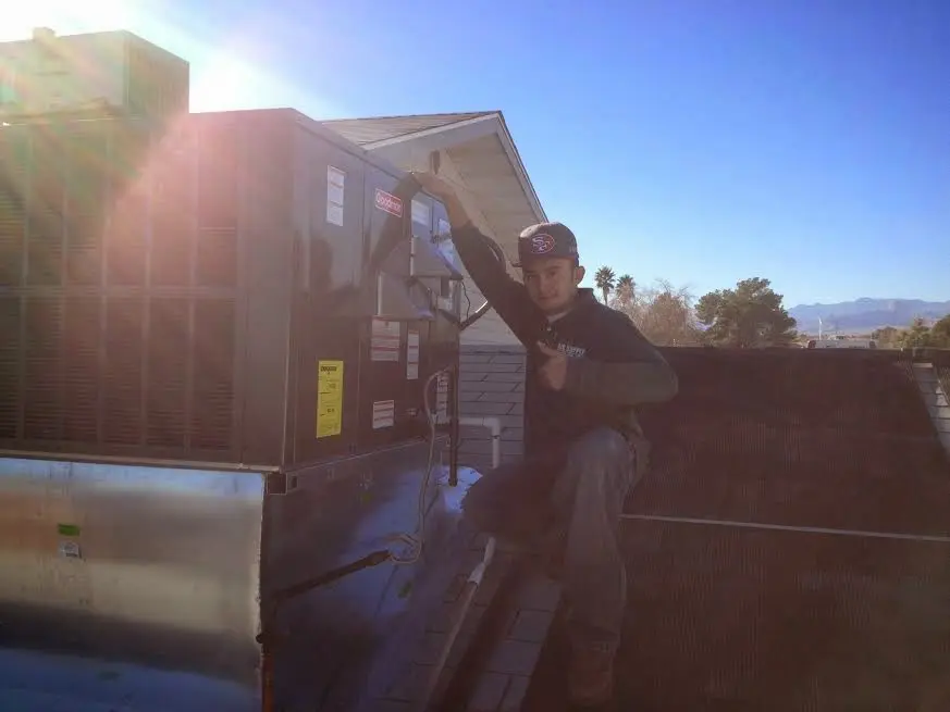 HVAC technician performing Air Duct Cleaning on a rooftop unit in Larose